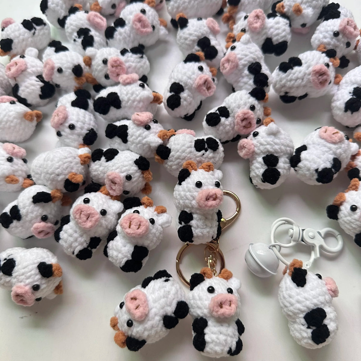 A collection of handmade crochet cow keychains in white and black yarn.