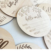 A collection of natural wood baby milestone discs with engraved details for newborn photography.