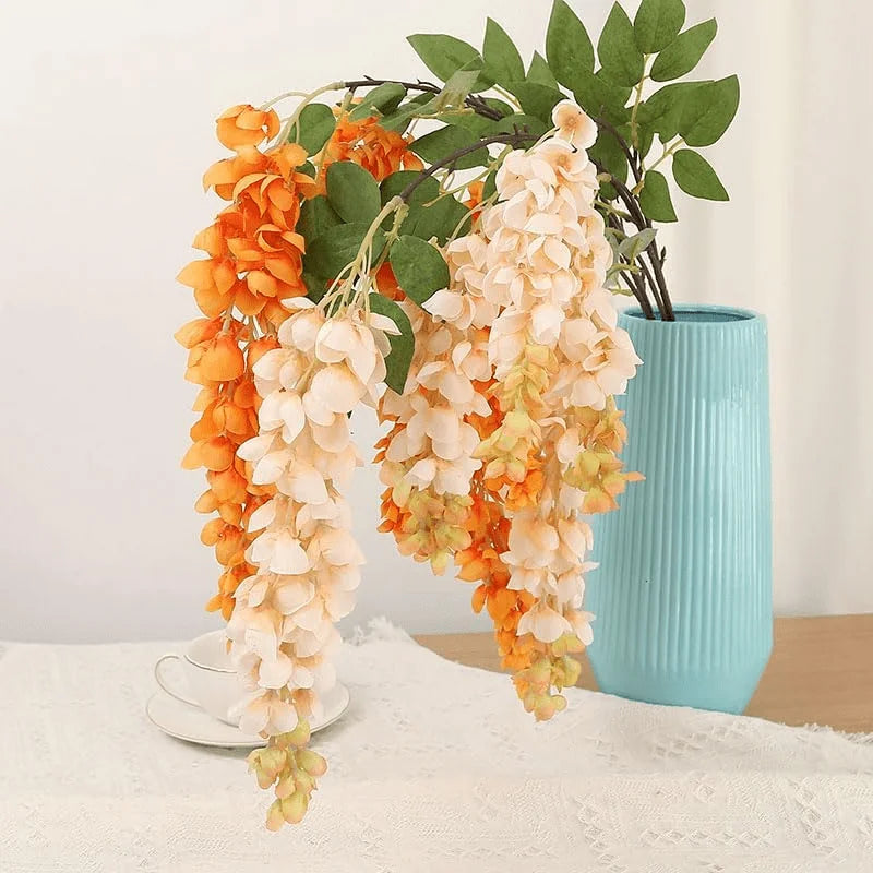Artificial wisteria hanging vine with orange and cream silk blooms in a light blue vase
