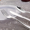 A set of gold disposable cutlery including forks, spoons, and knives resting on a white plate.