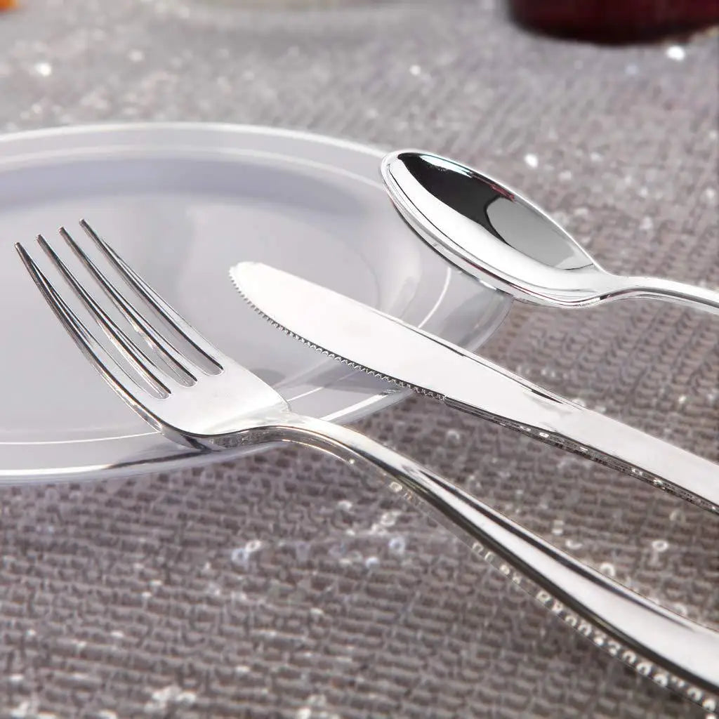A set of gold disposable cutlery including forks, spoons, and knives resting on a white plate.