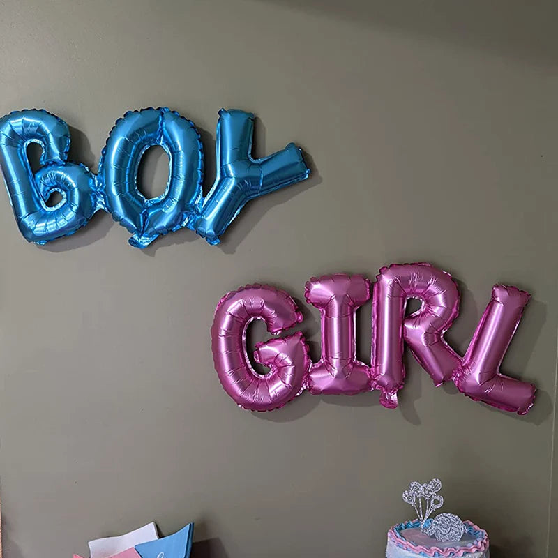 Blue and pink foil letter balloons spelling BOY and GIRL displayed on a wall.