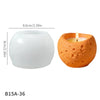 An orange textured silicone mold for candles with a lit wick, shown next to a smooth white bowl.