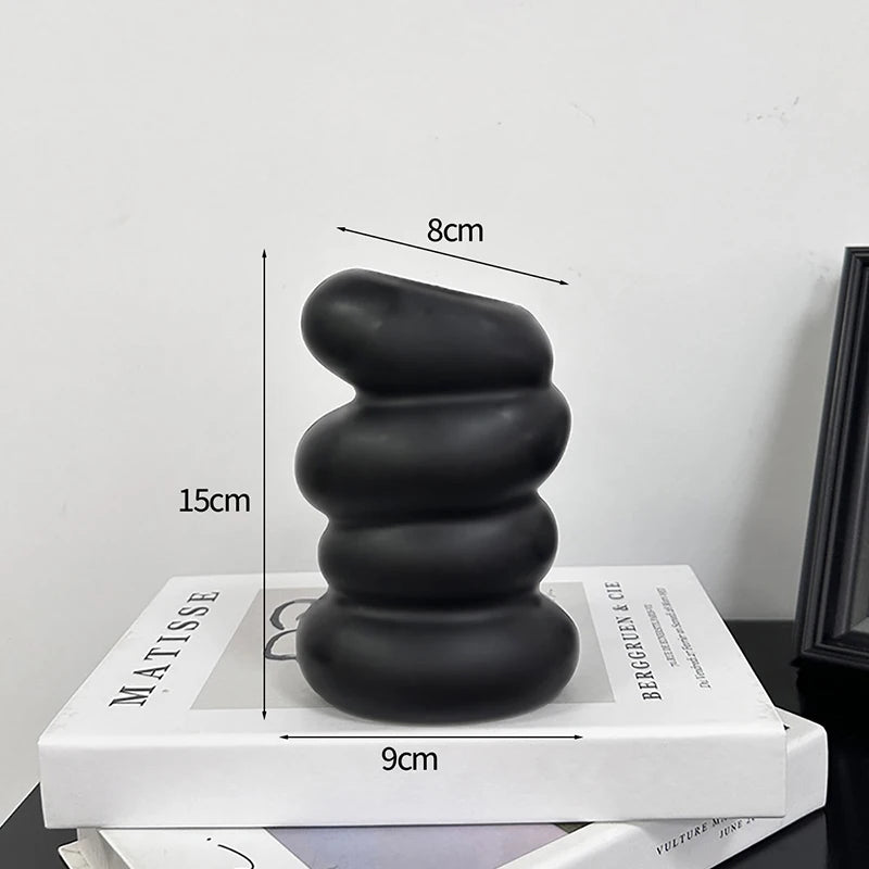 A stack of smooth black river stones on a white book, demonstrating their size.