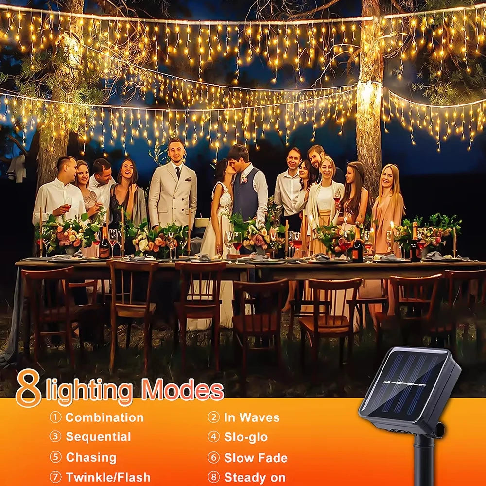String of solar LED icicle lights hanging outdoors with a group posing beneath them.