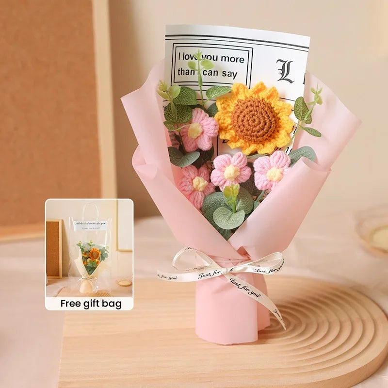 A pink paper bouquet featuring a sunflower and pink flowers with a card that reads I love you more than I can say.