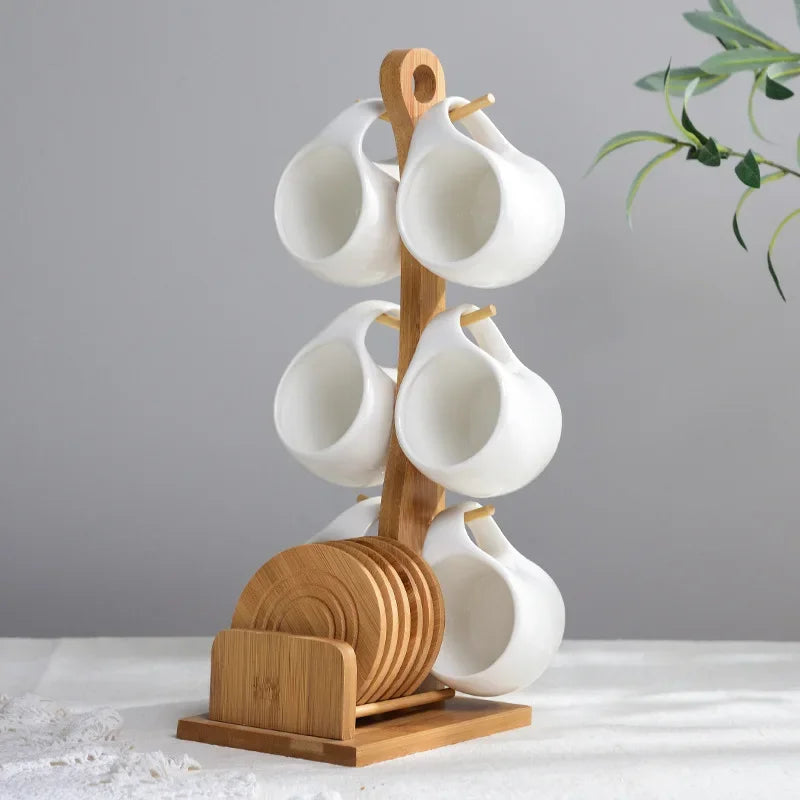 A ceramic coffee mug set with white mugs is displayed on a natural bamboo wood stand.