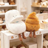 A white plush toy shaped like a toilet with a plunger, next to an orange plush toy shaped like a poop plunger.