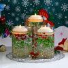 Three glass jars filled with water and green and red floating candles set against a Christmas-themed background