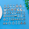 A collection of silver vintage ship anchor charms and nautical jewelry components laid out on a blue surface.