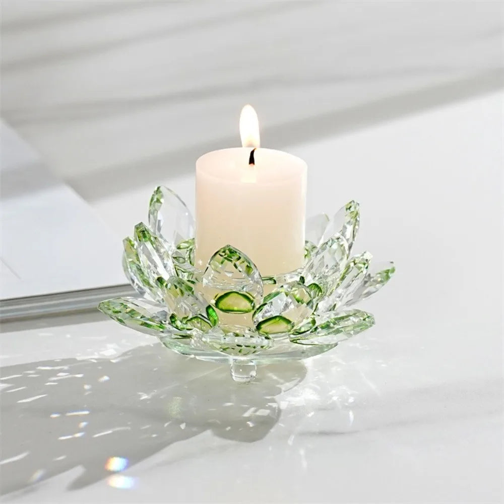 A clear glass lotus-shaped candle holder with a white candle and a lit wick, set on a white surface.