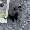 Black silhouette of a butterfly with swirling lines on a gray textured surface.