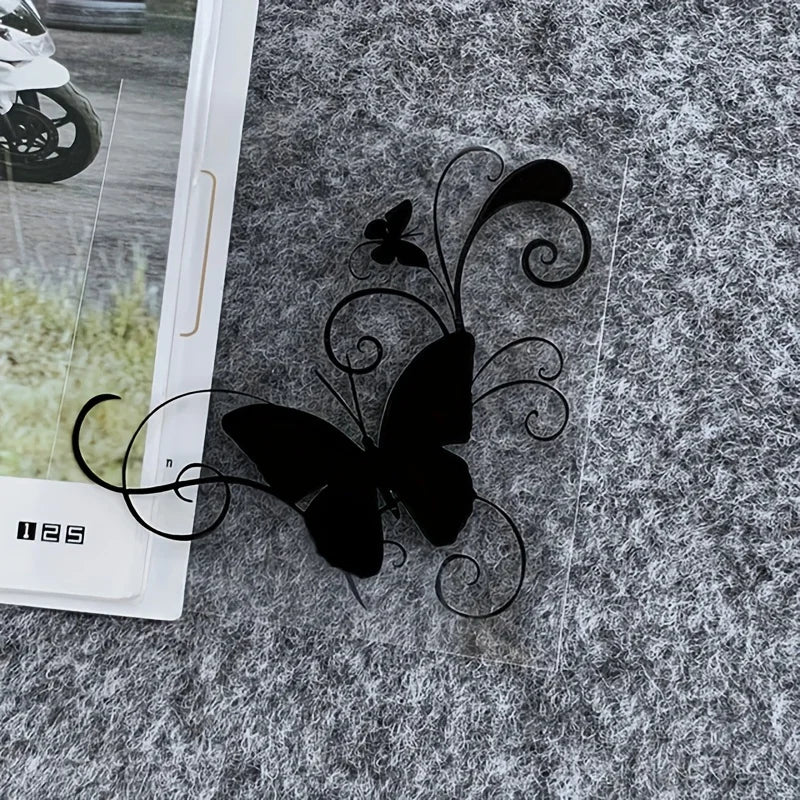 Black silhouette of a butterfly with swirling lines on a gray textured surface.