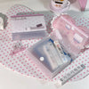 Una caja de almacenamiento minimalista rosa para pegatinas y tarjetas junto a una caja de chocolate y una taza blanca.