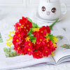 A vibrant bouquet of red and yellow artificial daisy flowers displayed on an open book next to a cute ceramic mug.