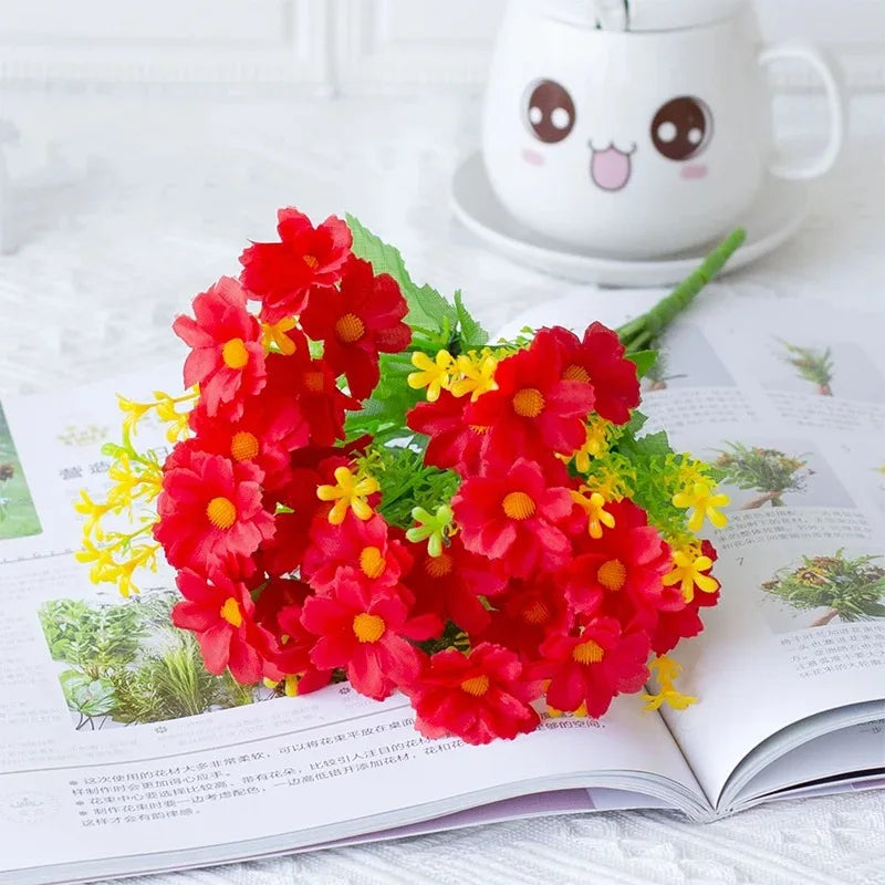 A vibrant bouquet of red and yellow artificial daisy flowers displayed on an open book next to a cute ceramic mug.
