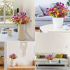 A collection of vibrant artificial flowers in various shades of purple, pink, and yellow displayed in white pots and vases.