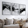A set of three black and white canvas prints depicting hands, used as wall art.