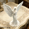 White gold praying angel figurine with outstretched wings standing on a decorative surface.