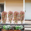 A row of vibrant pink and red faux silk flowers cascades from a white railing on an outdoor deck.