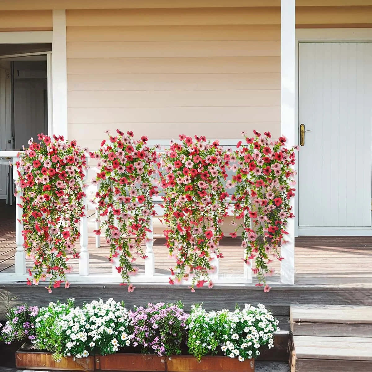 A row of vibrant pink and red faux silk flowers cascades from a white railing on an outdoor deck.