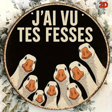 A circular wooden sign featuring several carved white duck heads against a black background, decorated with light gray foliag