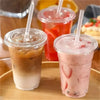 Three clear plastic cups filled with iced beverages, including tea and fruit smoothies, served on a wooden tray.
