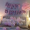 Pink and white foil letter balloons spelling happy birthday decorating a bedroom wall