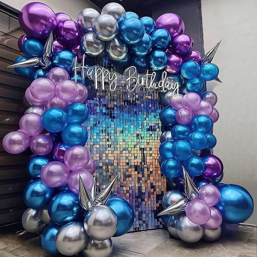 A colorful balloon arch decoration featuring purple and blue balloons with silver accents for a birthday party.