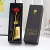A black gift box displaying a gold foil rose flower and a card, set against a white background.