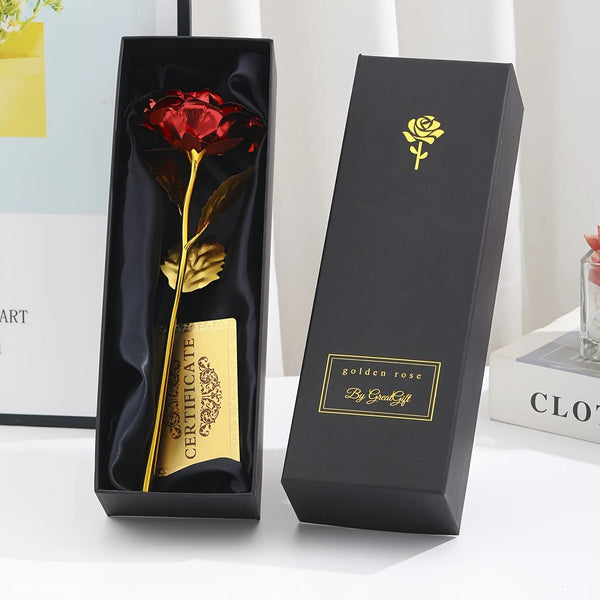 A black gift box displaying a gold foil rose flower and a card, set against a white background.