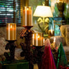 A collection of glowing glass pillar candles in various sizes and colors displayed on a table.
