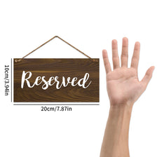 A rustic wooden sign with the word Reserved is displayed next to a human hand for scale.