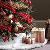 A festive Christmas tree decorated with red ribbons and ornaments resting on a white faux fur surface.
