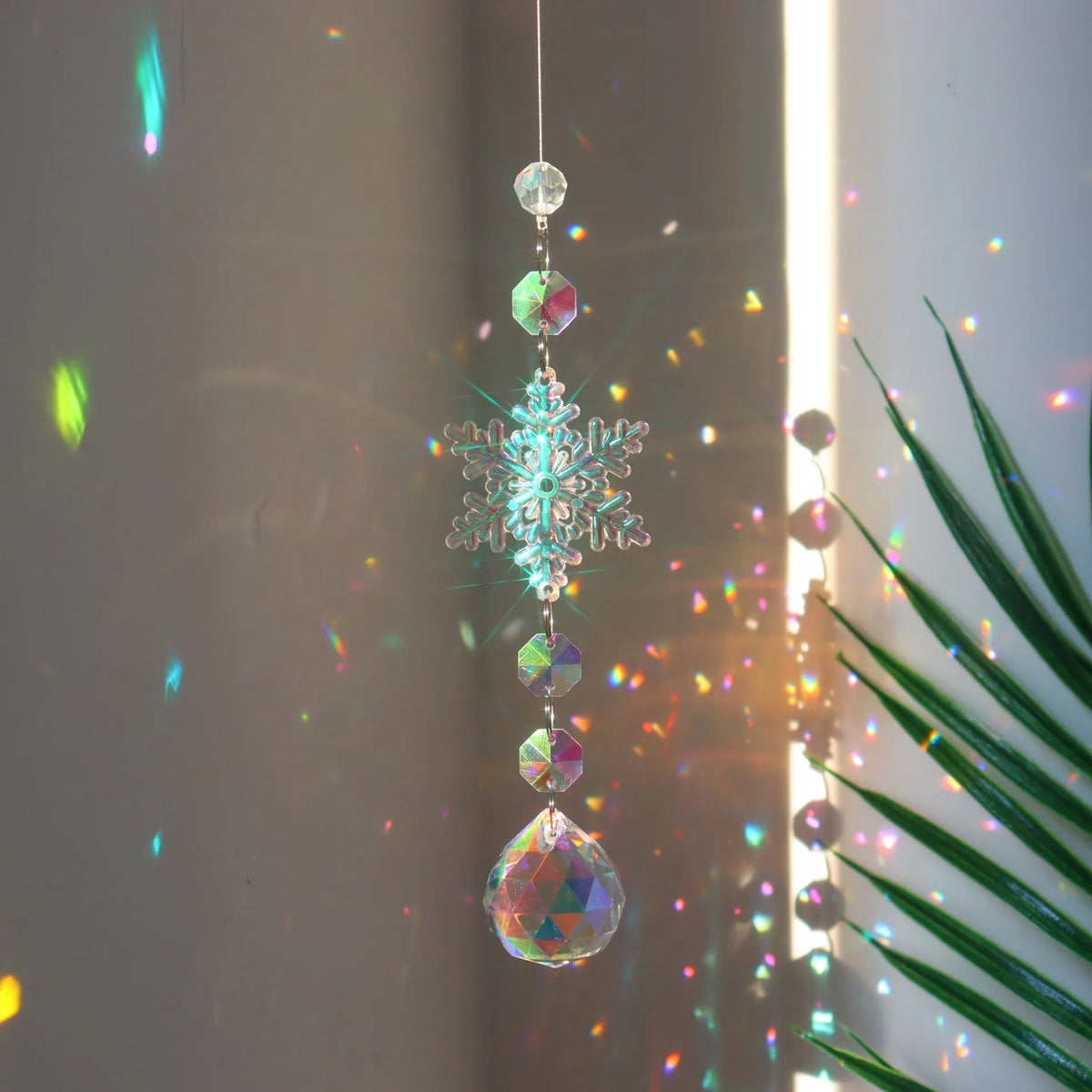 A hanging crystal rainbow wind chime featuring a central snowflake and multiple iridescent glass beads.