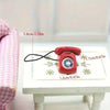 A red retro rotary desk phone miniature is shown on a white surface with dimension markings.
