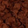 Dark brown artificial silk rose petals scattered on a surface.