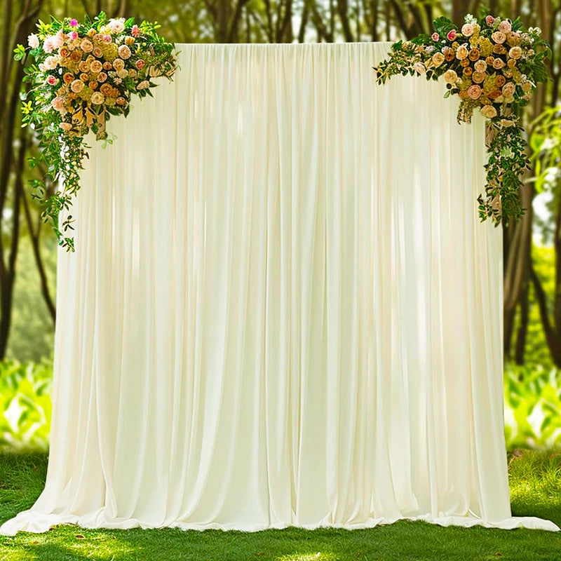 A cream fabric backdrop curtain decorated with floral greenery and roses outdoors.