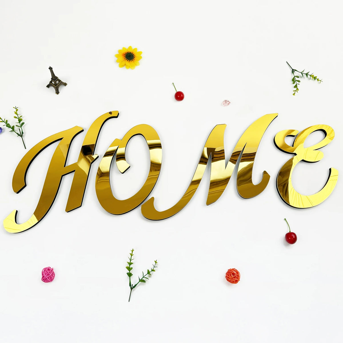 Gold 3D acrylic letter wall stickers spelling HOME with small decorative leaves and berries