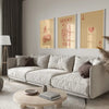 A modern living room features a light sofa and decorative pillows with framed retro letter art paintings on the wall.
