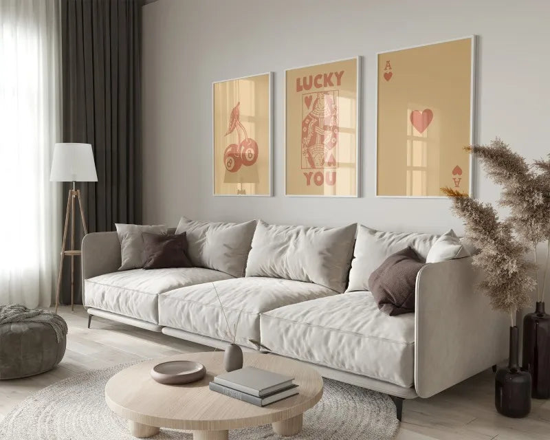 A modern living room features a light sofa and decorative pillows with framed retro letter art paintings on the wall.