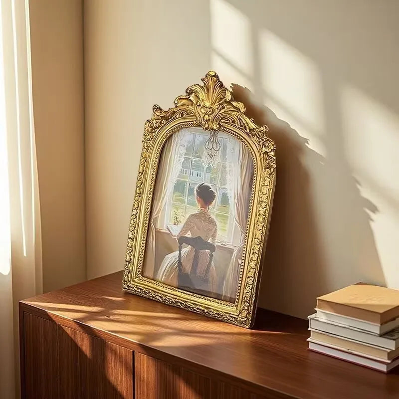 An ornate gold-framed vintage resin photo frame displaying a sepia-toned portrait of a woman.