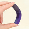 A hand holds a purple, curved magnetic dry erase label or sticker.