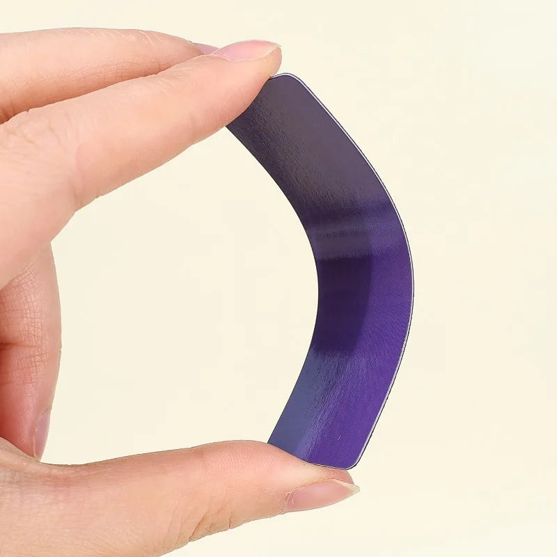 A hand holds a purple, curved magnetic dry erase label or sticker.