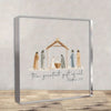 A framed artwork depicting a nativity scene with figures under a wooden shelter and the text The greatest gift of all Matthew