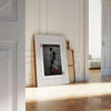 A framed playing card featuring a black and white photo of a couple, presented in a light wood frame.