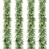A vertical display of an artificial eucalyptus vine garland featuring green leaves and white flowers.