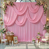A pink fabric backdrop curtain decorated with floral garlands and draped fabric for an event.