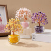 Three natural crystal money tree ornaments in pink, yellow, and purple displayed on a light background.