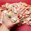 A hand holds a pile of assorted Christmas resin fridge magnets featuring Santa, snowmen, and tree designs.